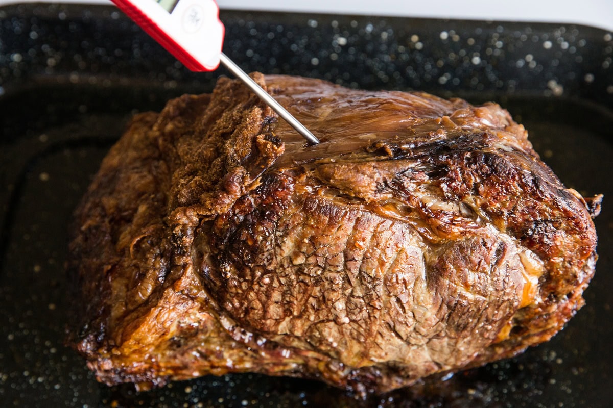 Roasted prime rib with a thermometer sticking out, taking its temperature.