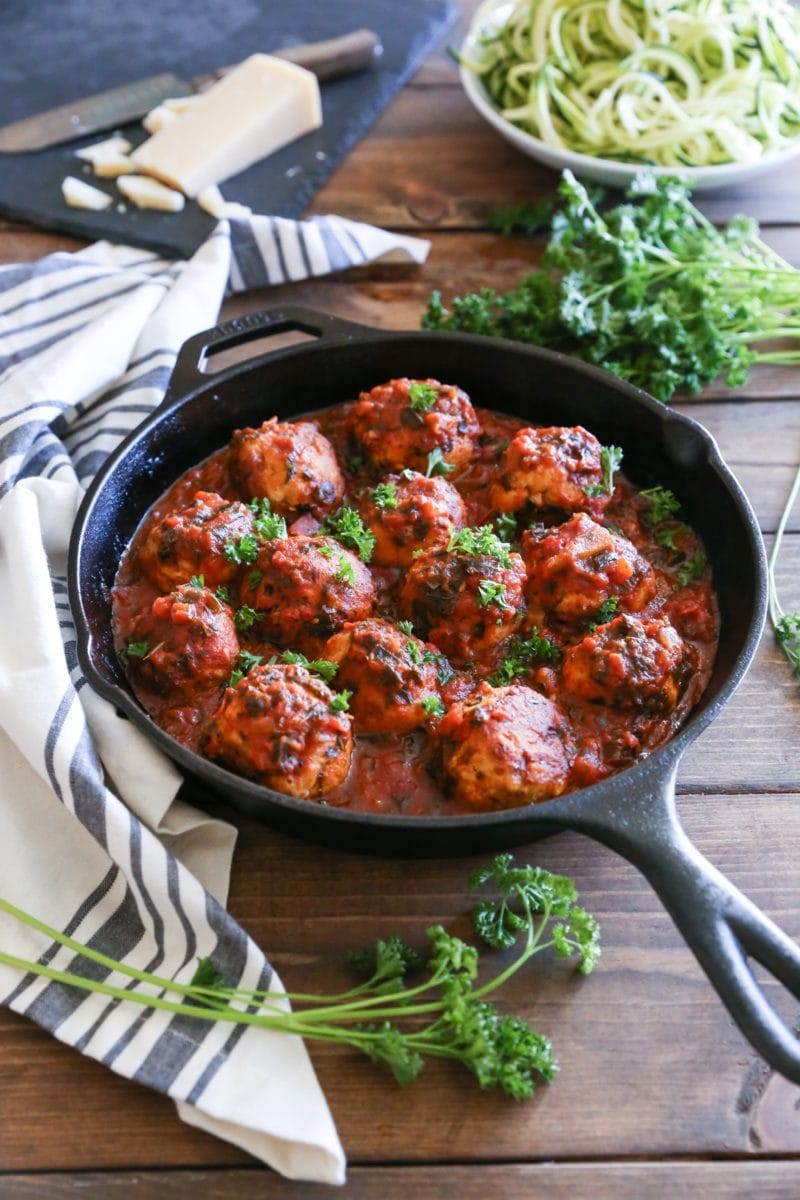 Cast iron skillet on a wooden table with a napkin and fresh parsley