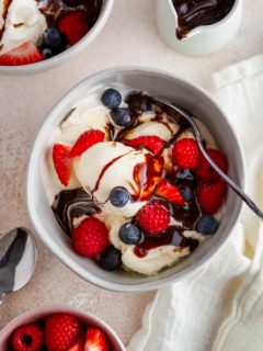 Homemade vanilla ice cream in a bowl with fresh berries and chocolate sauce, ready to eat