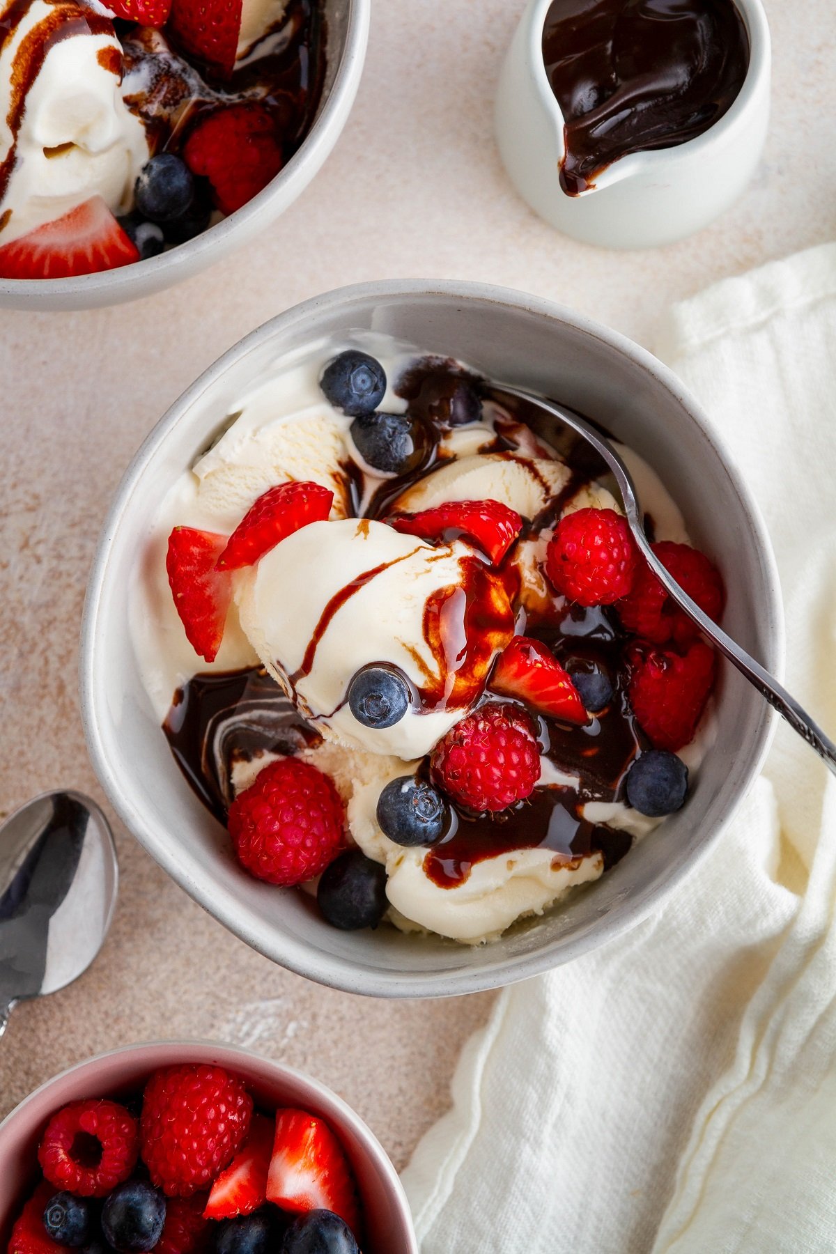 Homemade vanilla ice cream in a bowl with fresh berries and chocolate sauce, ready to eat