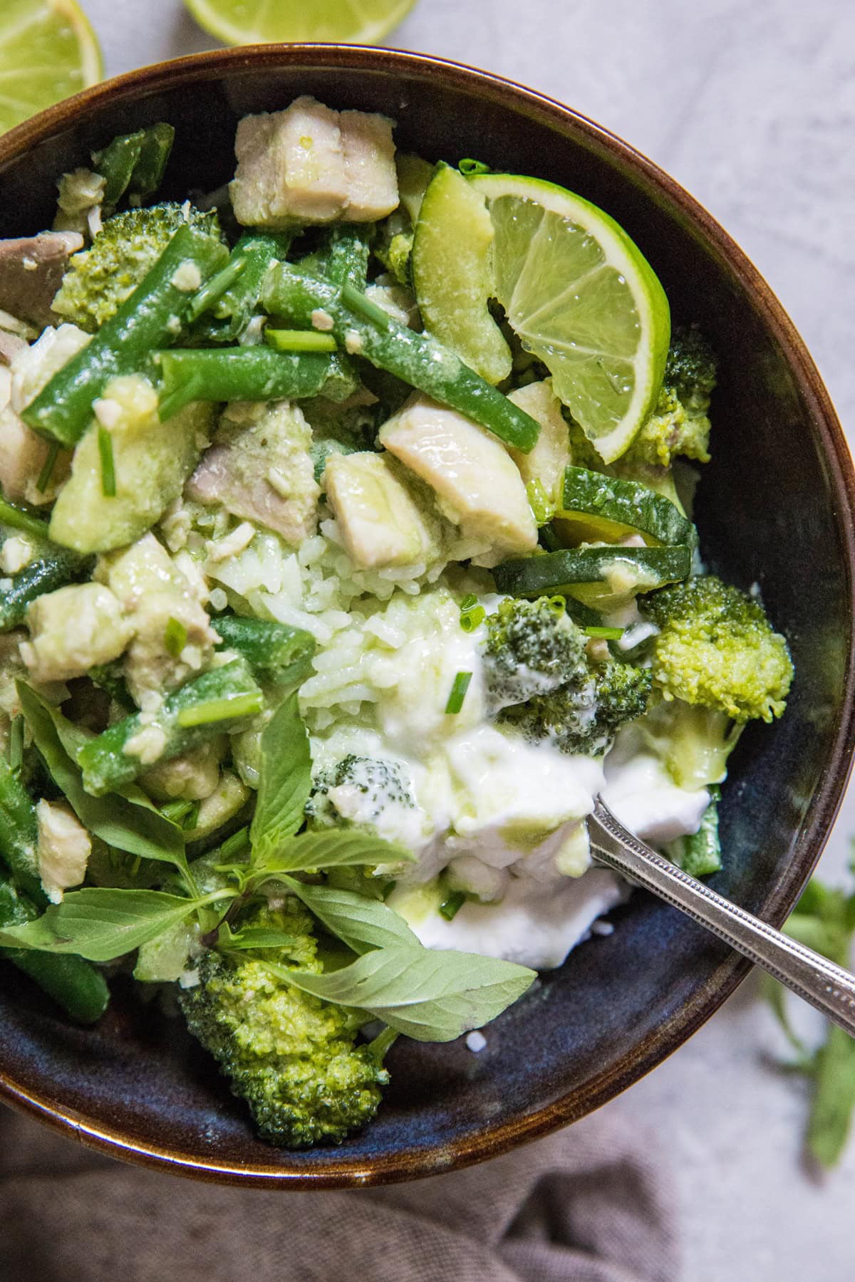 close up top down photo of bowl of fish green curry with a fork inside