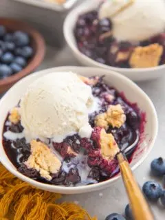 Two bowls of blueberry cobbler with ice cream on top.