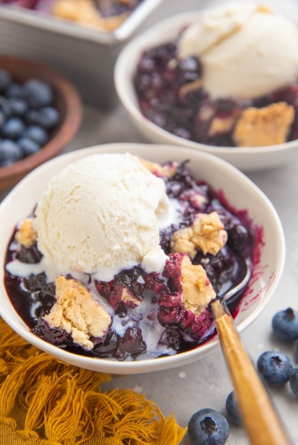 Two bowls of blueberry cobbler with ice cream on top.