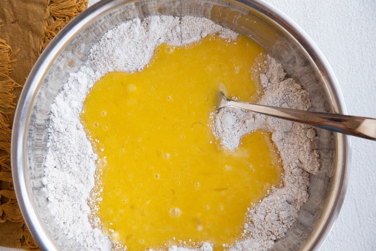 Mixing bowl with dry ingredients in the bottom and wet ingredients on top, ready to be mixed into cake batter.