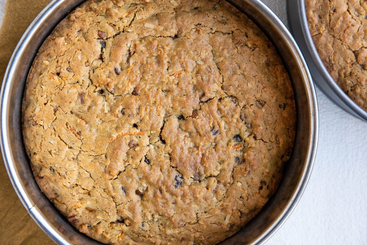 Two carrot cakes in cake pans fresh out of the oven.