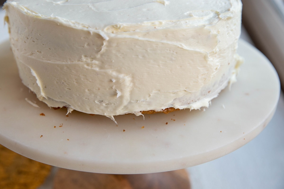 Fully frosted carrot cake on a cake stand.