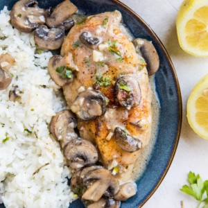 Blue plate of gluten-free chicken marsala with white rice to the side.