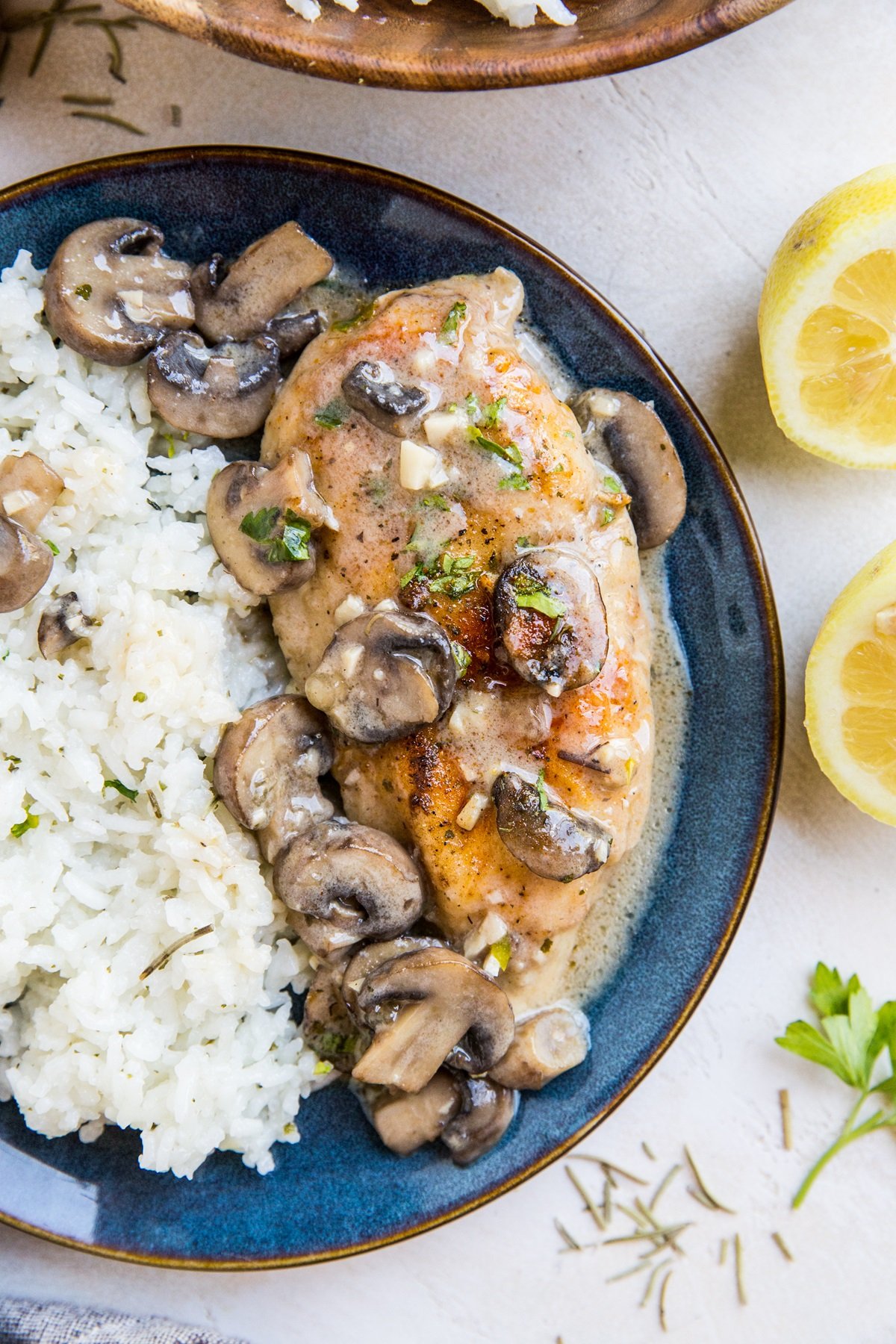 Blue plate of gluten-free chicken marsala with white rice to the side.