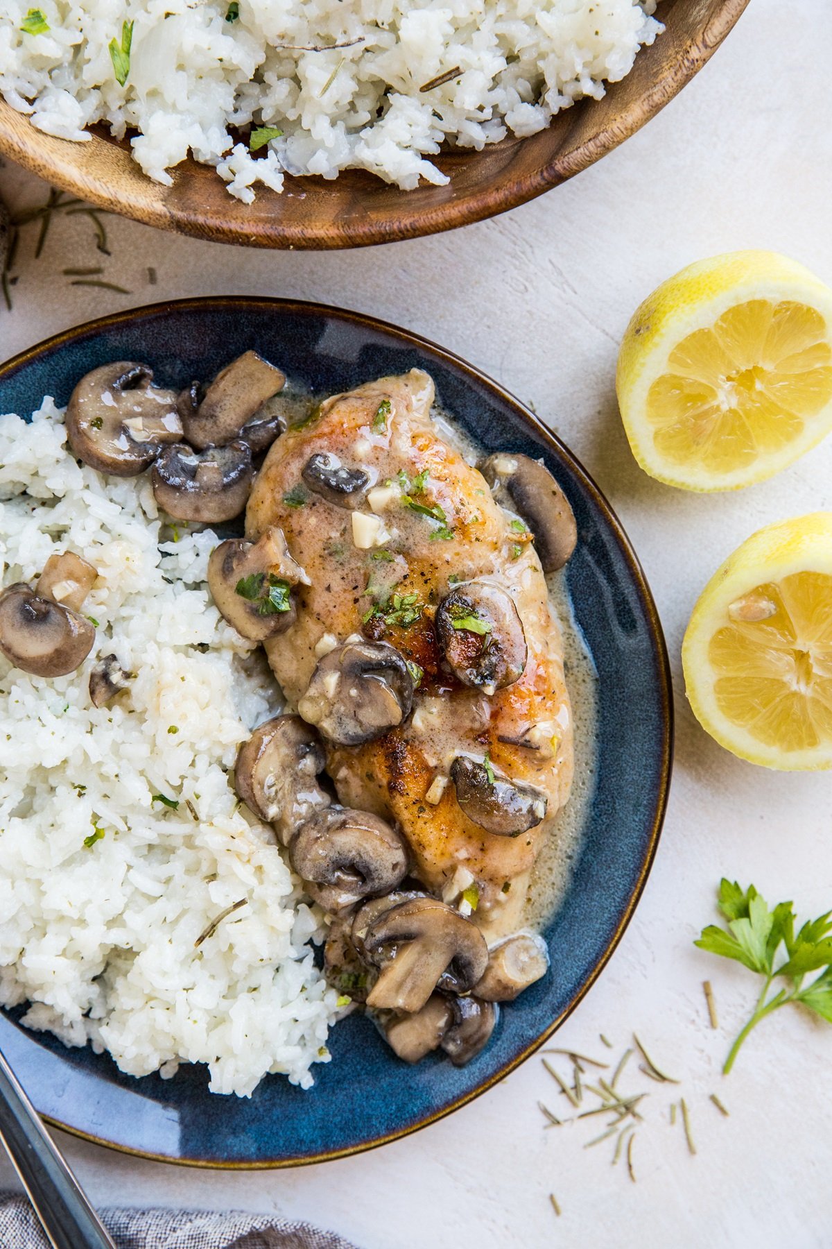 Gluten-free chicken marsala on a blue plate with white rice. Fresh herbs to the side.