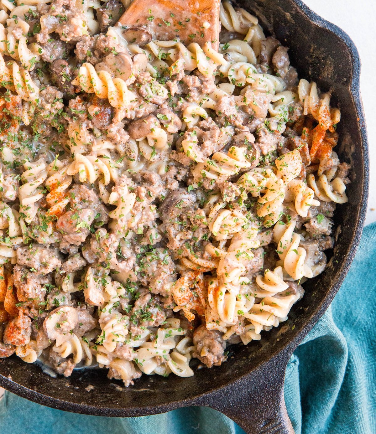 Cast iron skillet full of gluten-free ground beef stroganoff and a blue napkin to the side.