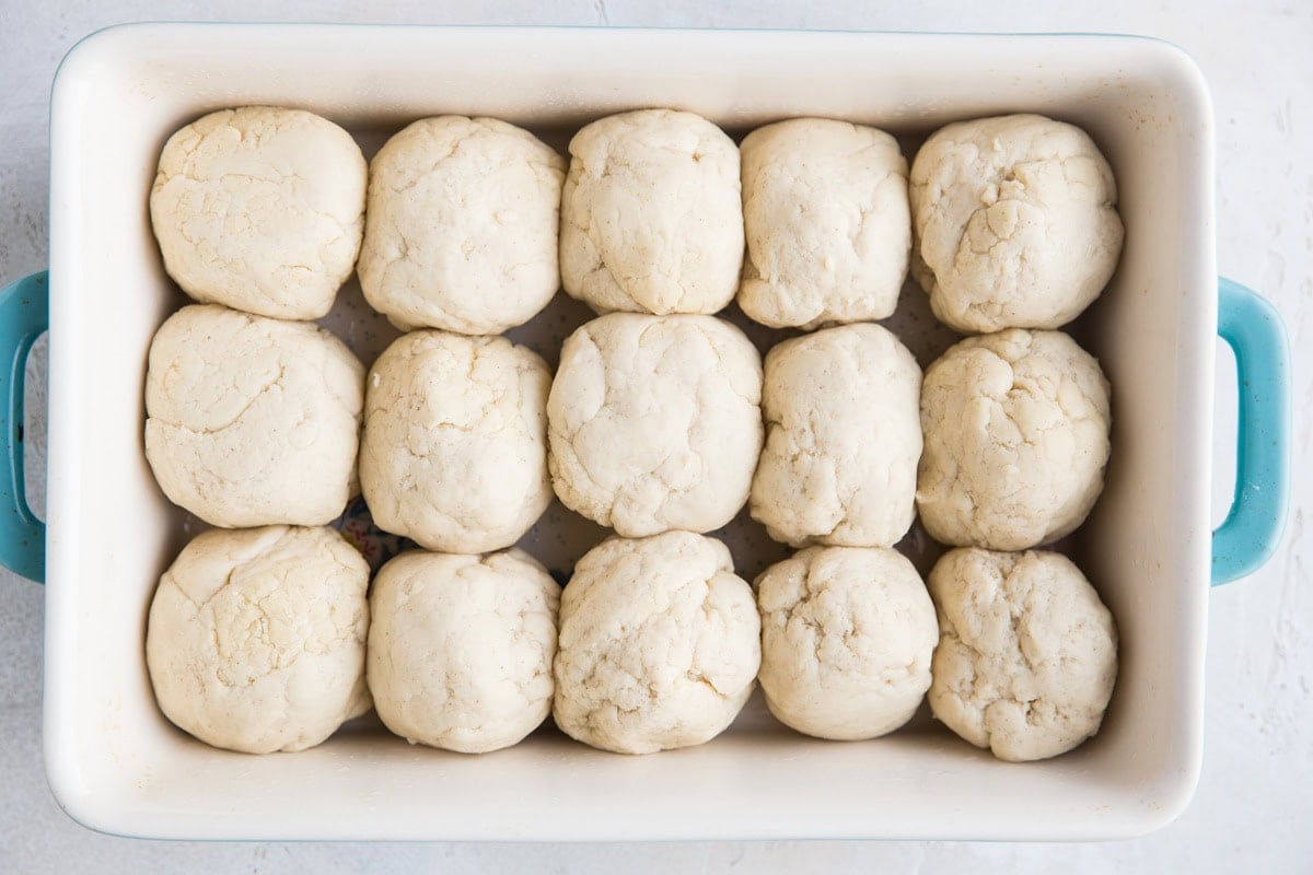 Rolled dough balls in a large casserole dish, waiting to sit for the dough to rise.