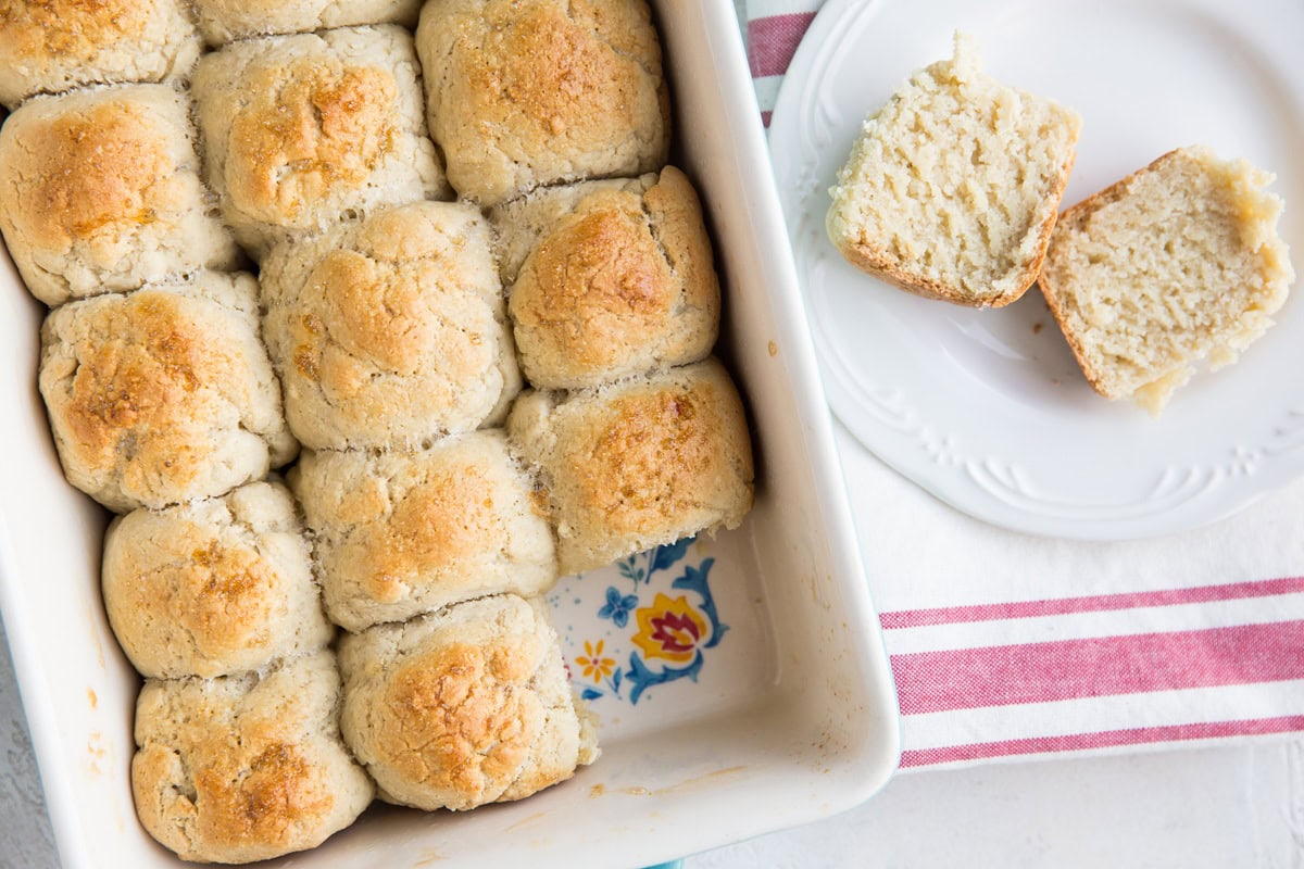 Hawaiian Rolls in a baking dish with a plate with a roll to the side.