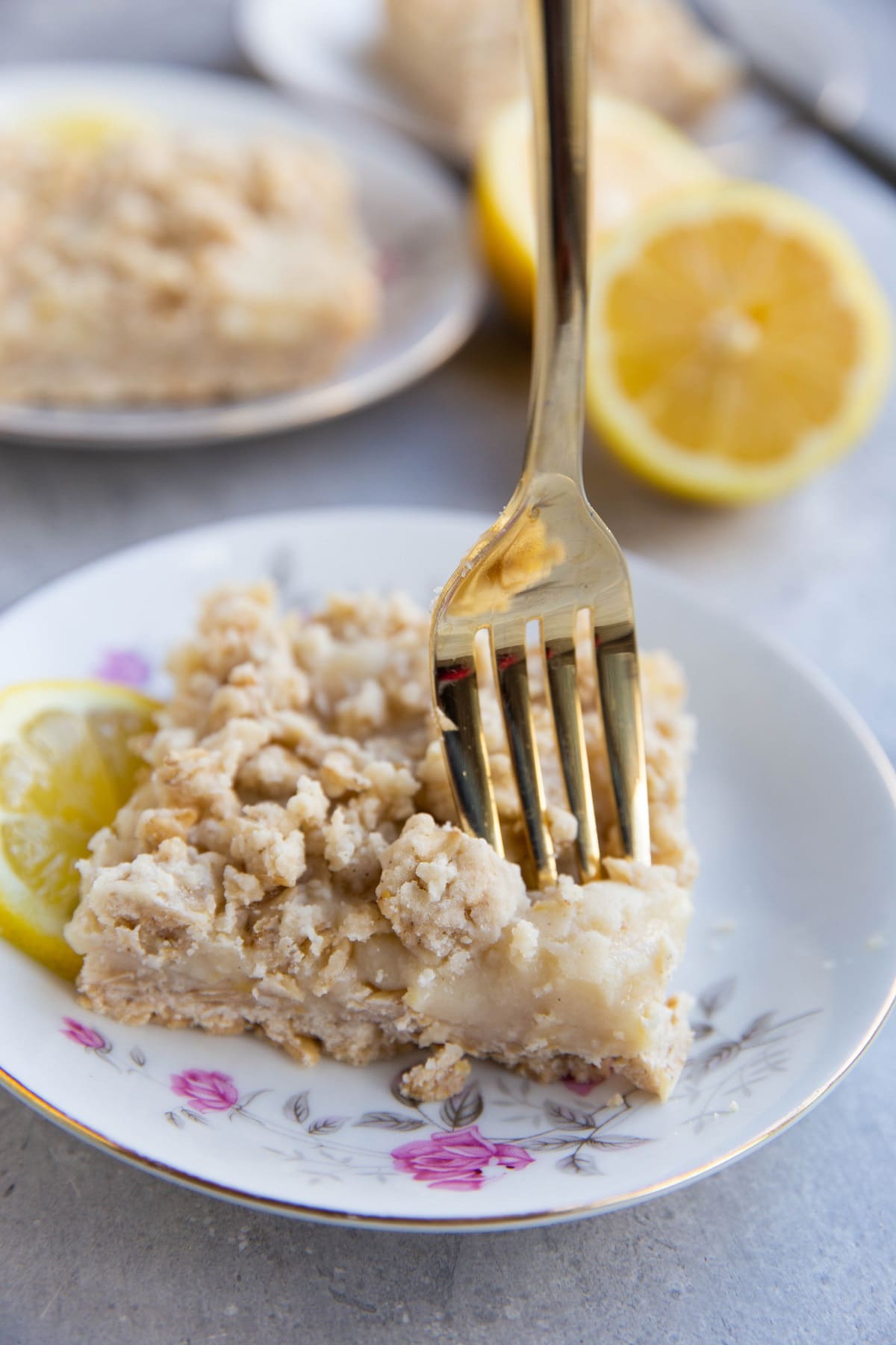 Slice of lemon bar on a plate with a fork taking a bite out.
