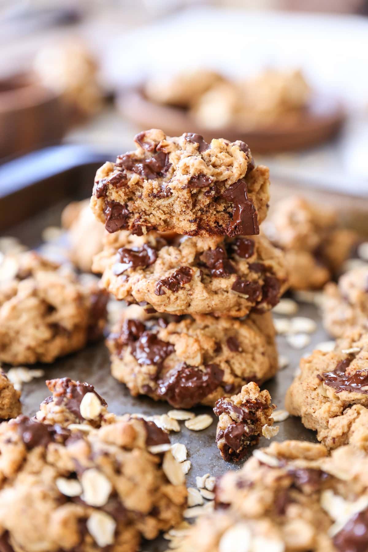 Stack of three gluten-free chocolate chip oatmeal cookies on a baking sheet with more cookies to the side.