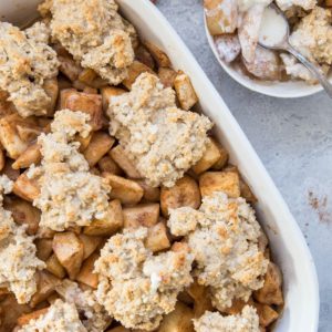Casserole dish full of pear cobbler with an individual portion in a bowl.