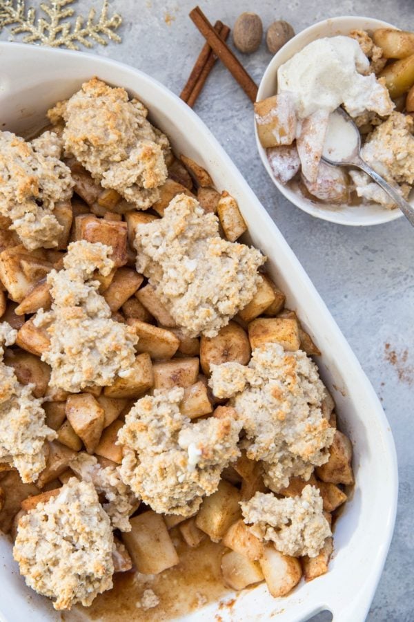 Casserole dish full of pear cobbler with an individual portion in a bowl.