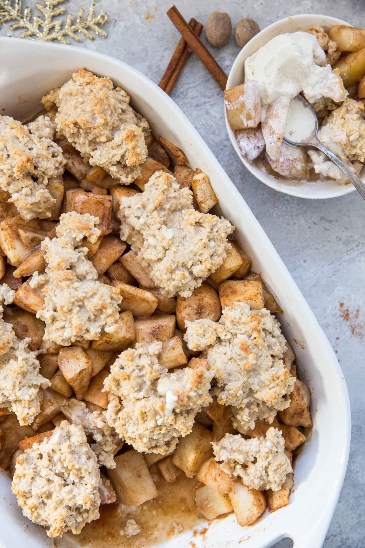 Casserole dish full of pear cobbler with an individual portion in a bowl.