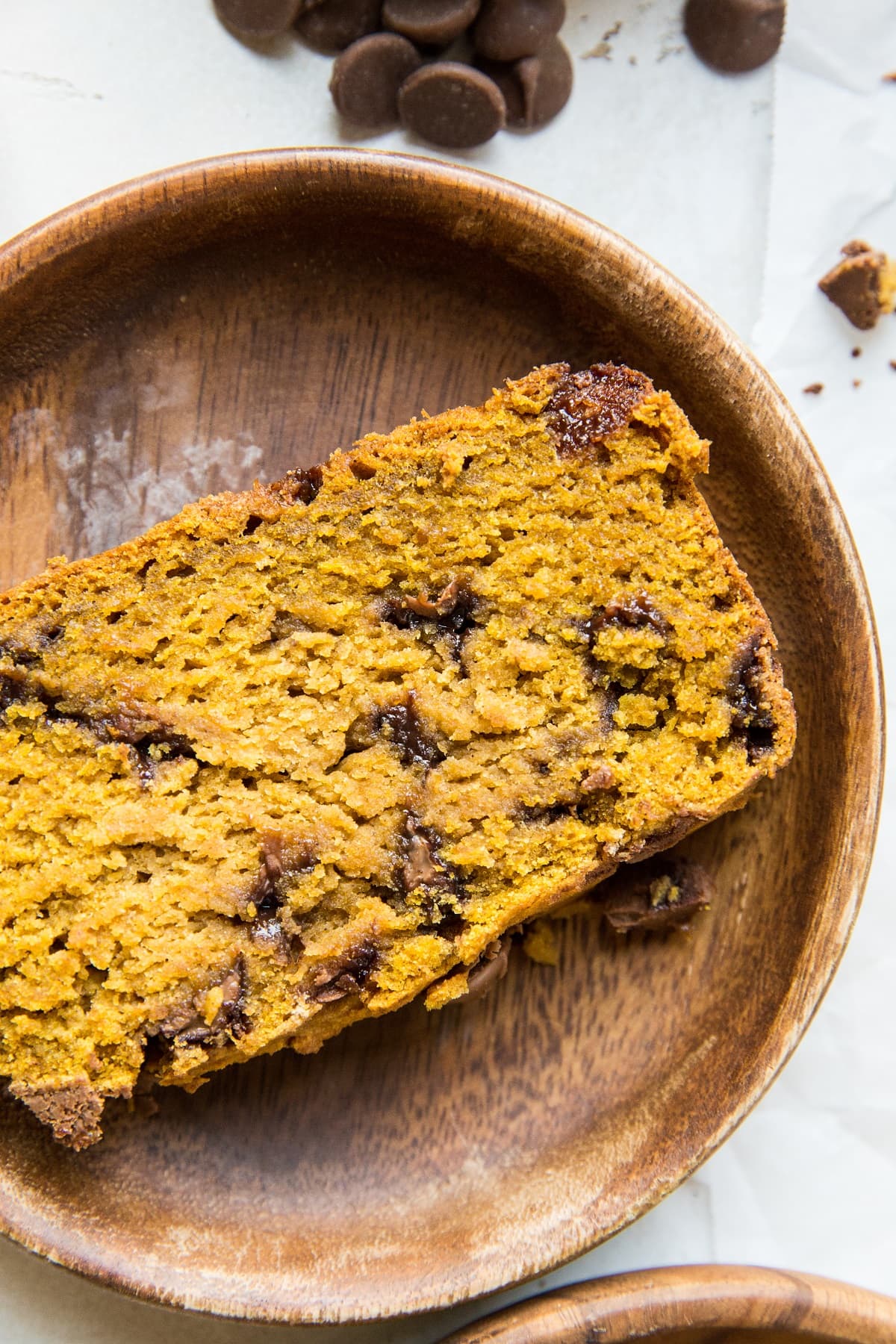 Slice of pumpkin bread on a wooden plate, ready to eat.