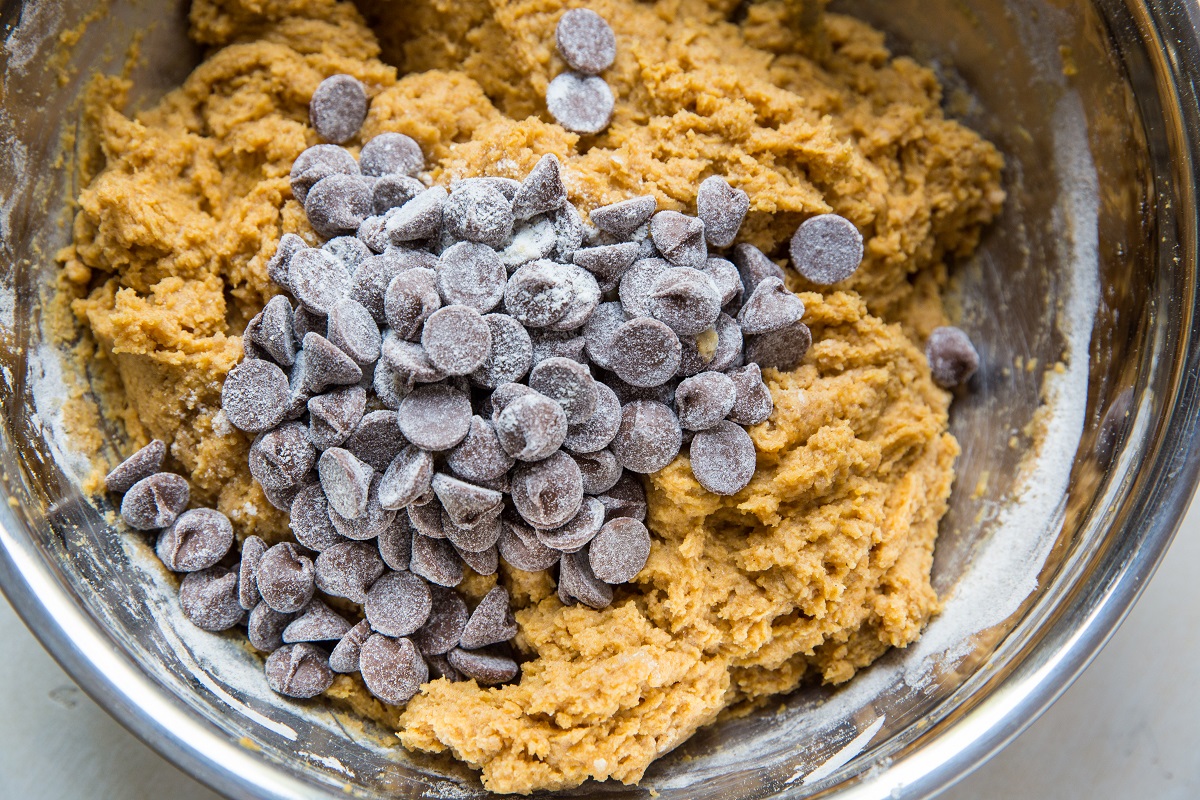 Chocolate chips on top of pumpkin loaf batter, ready to be mixed in.