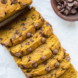 Sliced pumpkin loaf on a sheet of parchment paper.