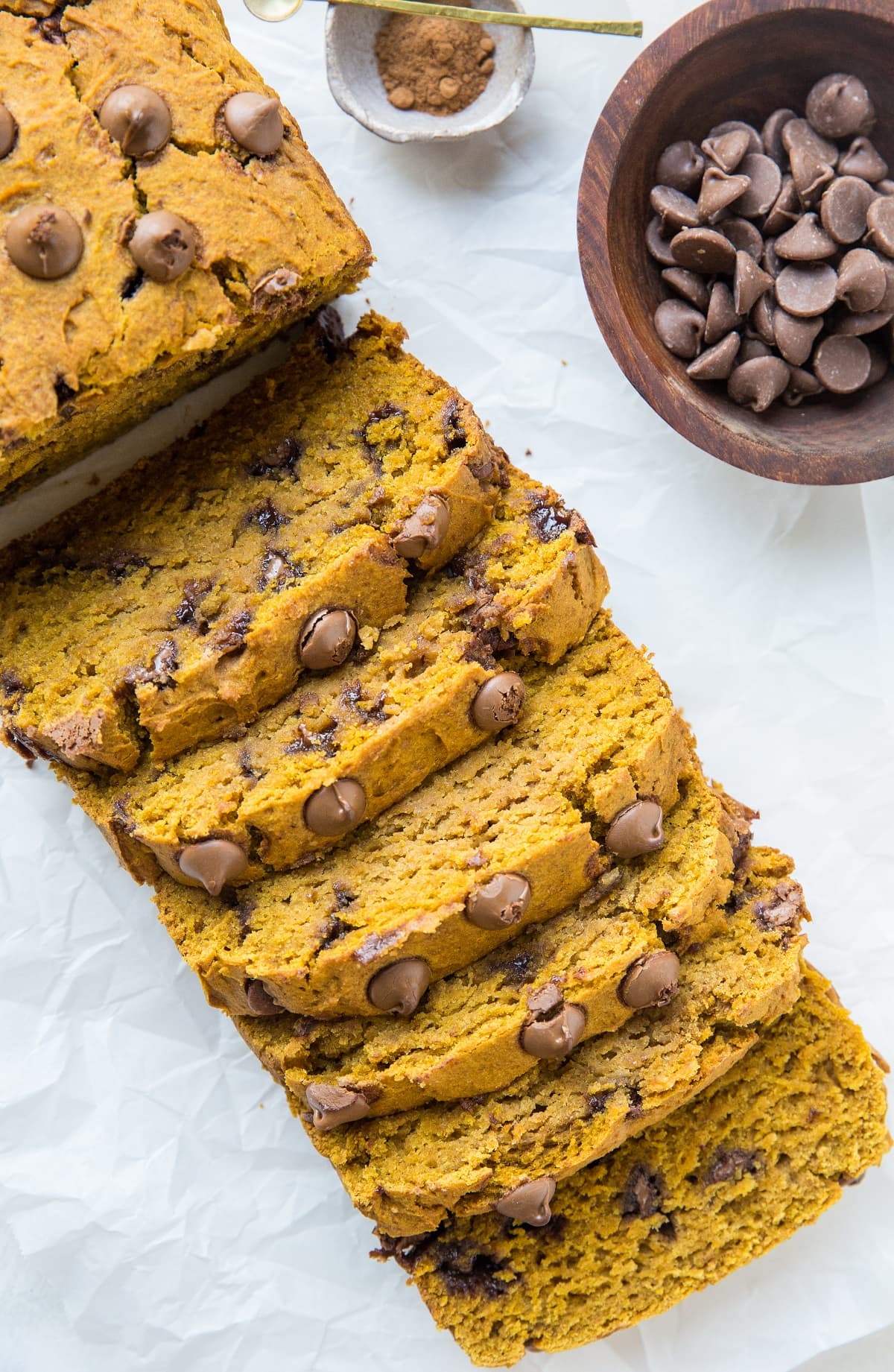 Sliced pumpkin loaf on a sheet of parchment paper.