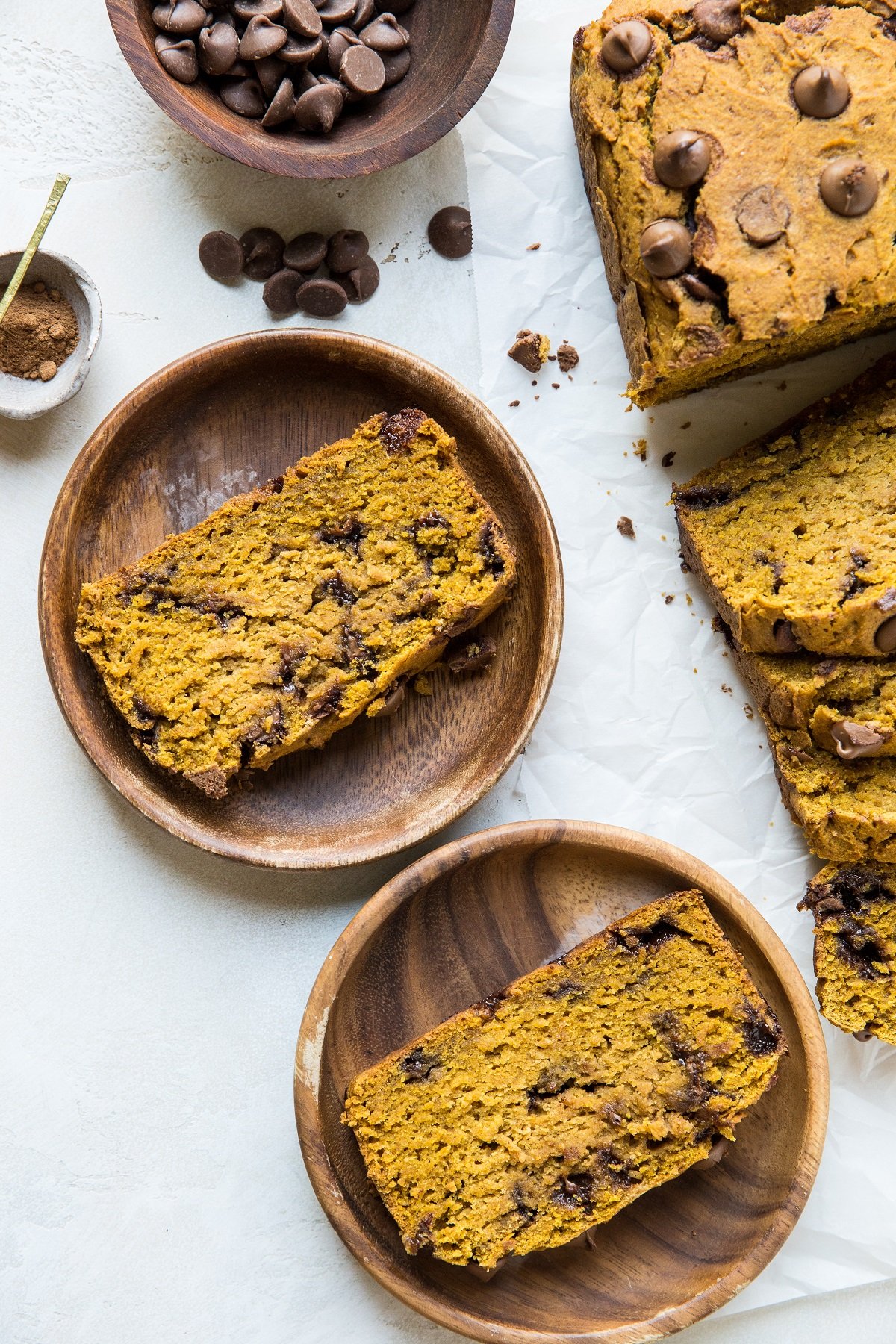 Two wooden plates with slices of pumpkin bread and the rest of the loaf off to the side.