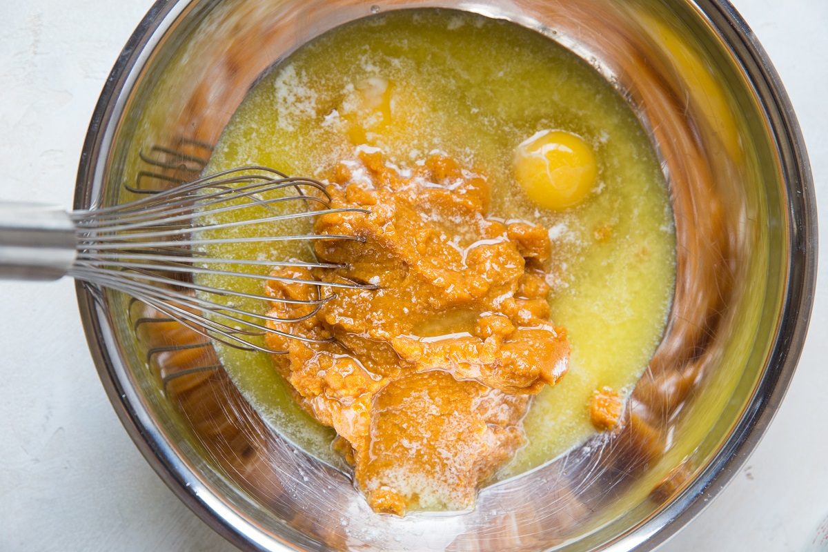 Melted butter, pumpkin puree and eggs in a mixing bowl, ready to be mixed up.