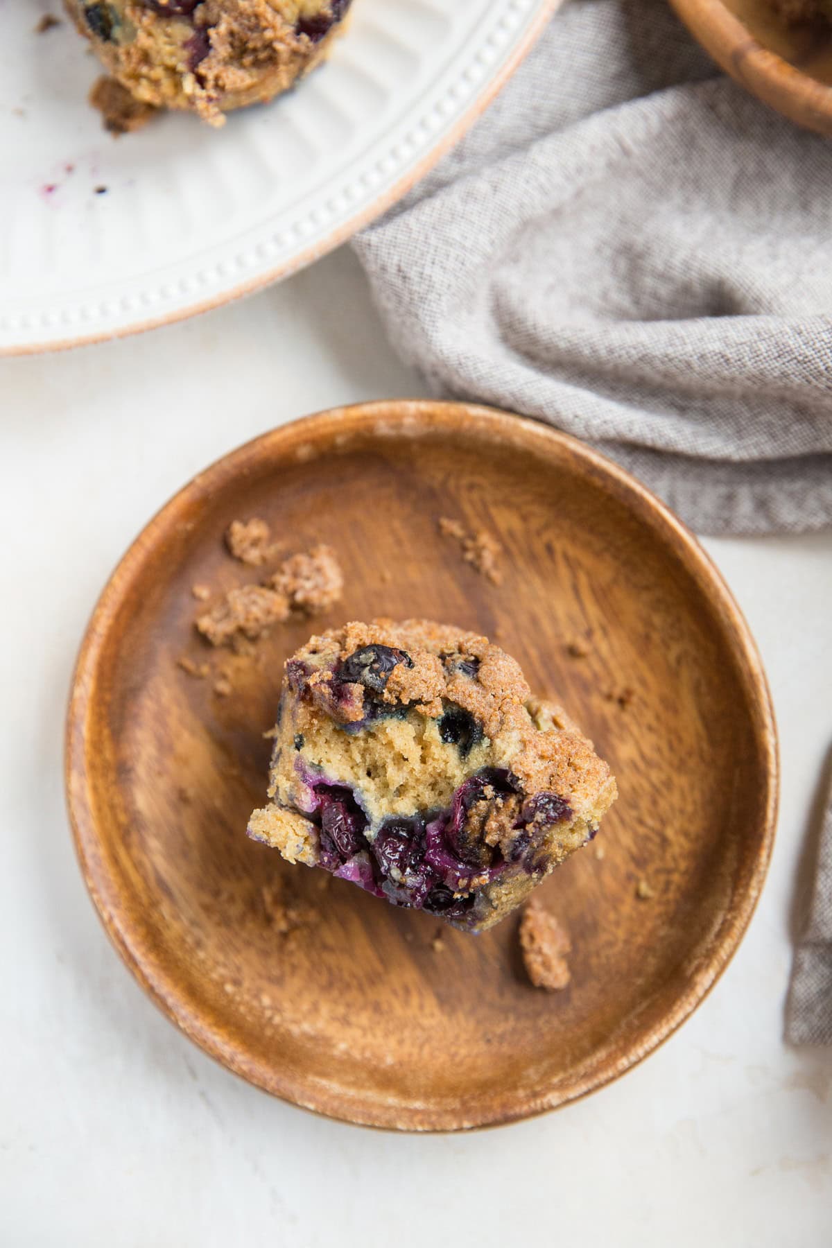 Three plates with blueberry sourdough muffins on them and a cloth napkin to the side