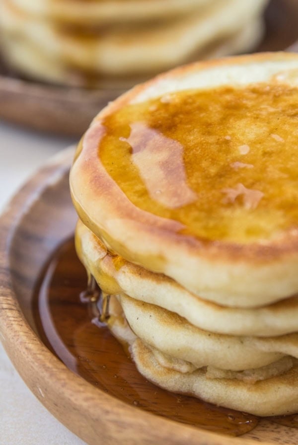 Close up shot of fluffy sourdough pancakes with syrup dripping down