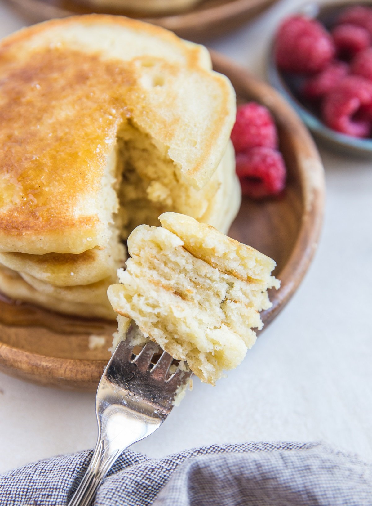 Stack of sourdough pancakes with bite taken out with a fork with layers of pancake on it.