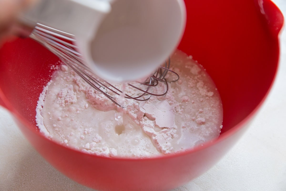 Water being poured into mixing bowl with flour to make sourdough starter
