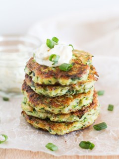Stack of Gluten Free Zucchini Fritters with Herb-Garlic Aioli on top and green onions garnishing.