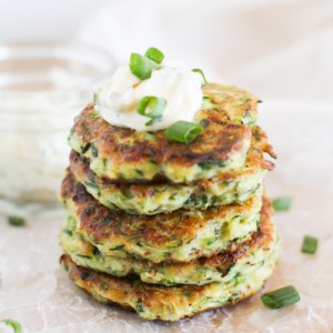 Stack of Gluten Free Zucchini Fritters with Herb-Garlic Aioli on top and green onions garnishing.