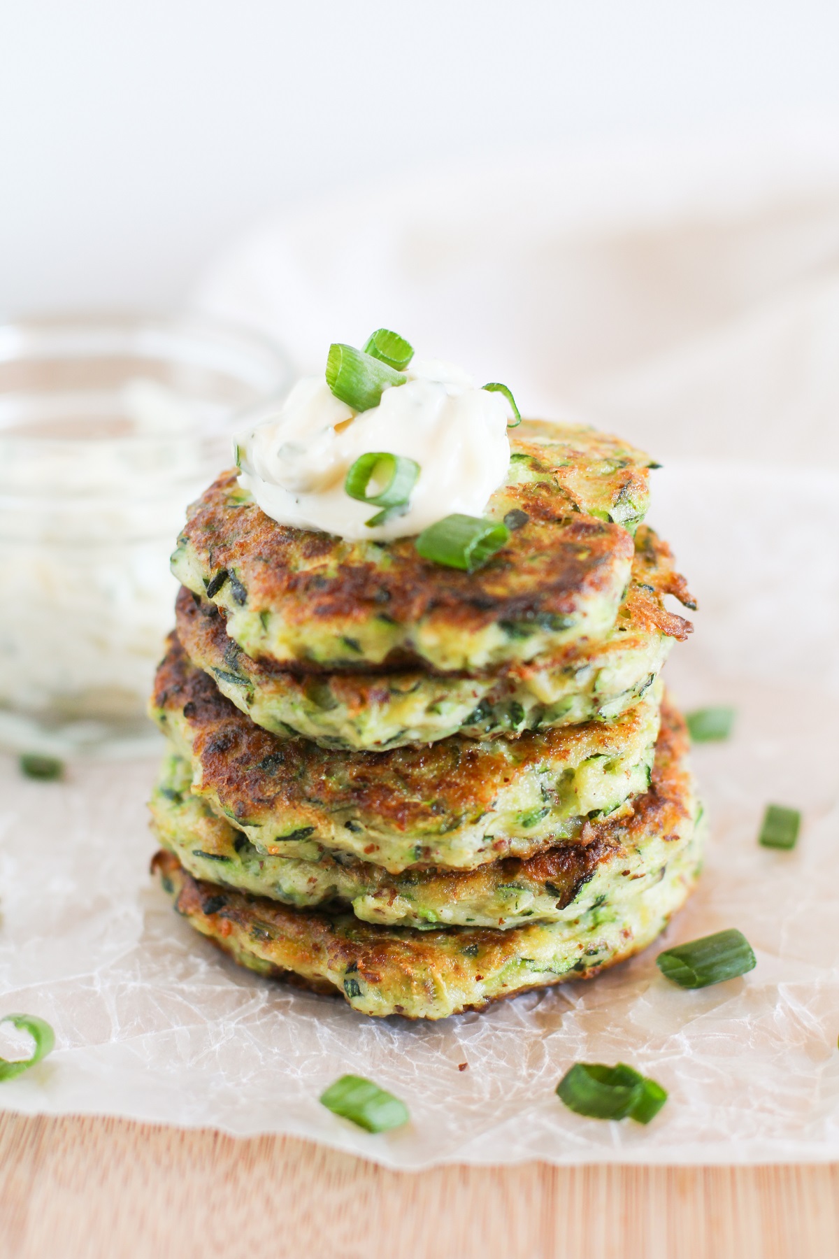 Stack of Gluten Free Zucchini Fritters with Herb-Garlic Aioli on top and green onions garnishing.