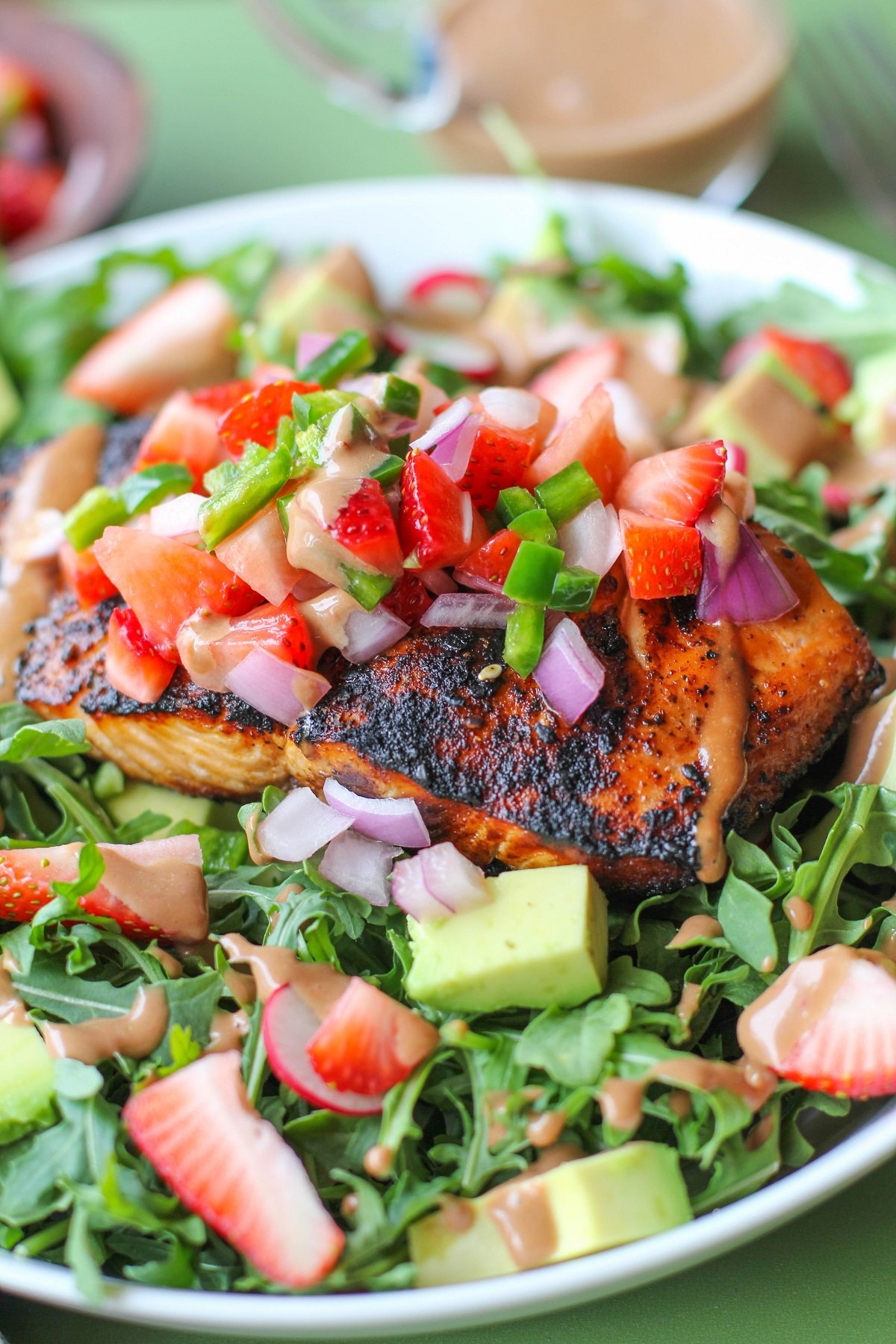 Grilled salmon on a bed of baby arugula with strawberry salsa, avocado, radishes and balsamic vinaigrette, ready to eat