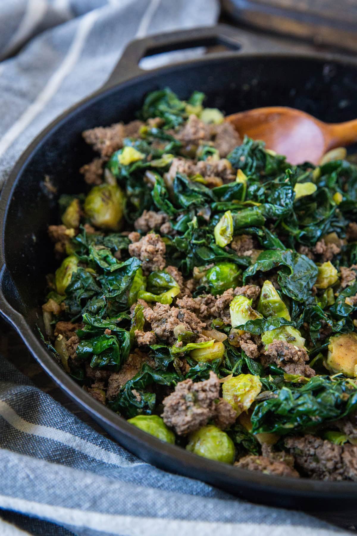 Skillet full of ground beef, kale, and brussels sprouts to use for stuffing winter squash.
