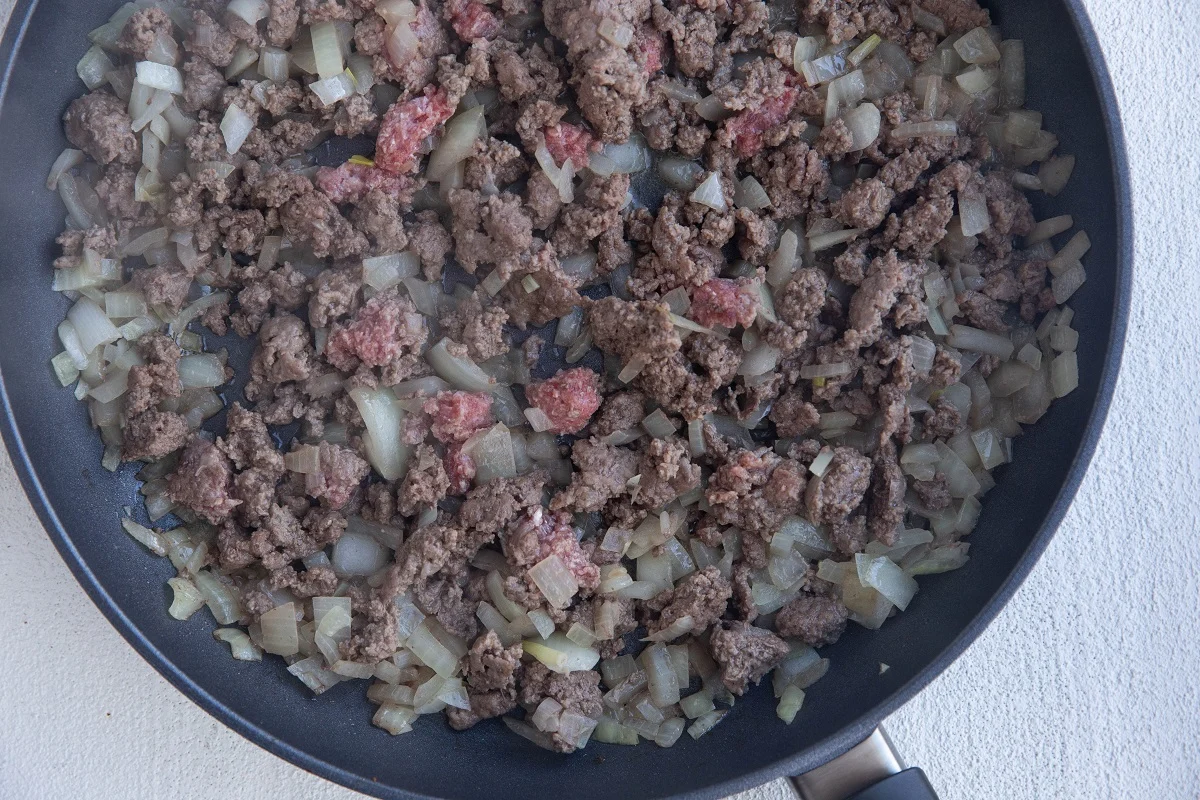 Ground beef and onions cooking in a skillet.