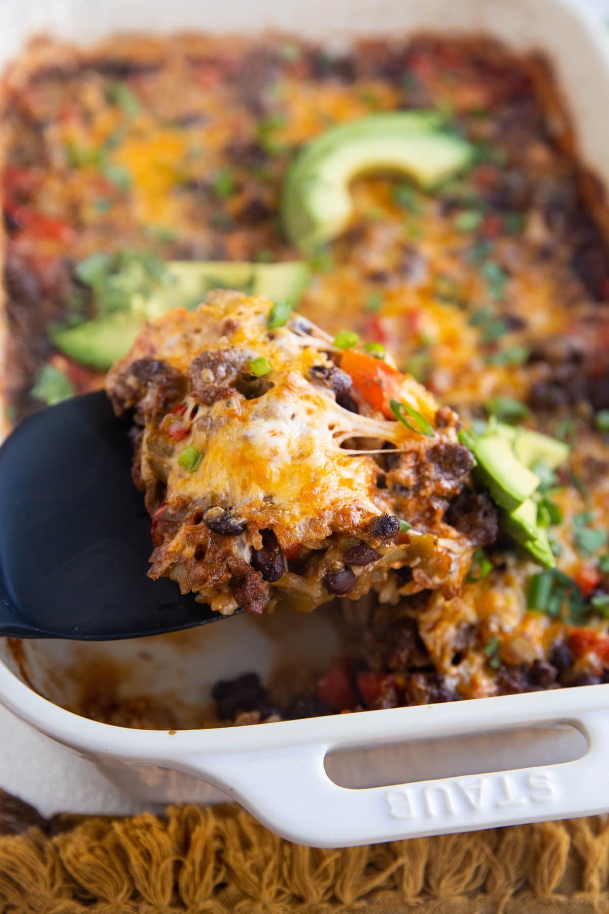 Spatula serving ground beef taco casserole.