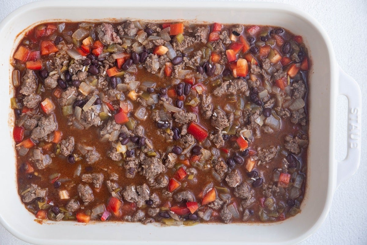 All of the ingredients for ground beef casserole in a casserole dish.