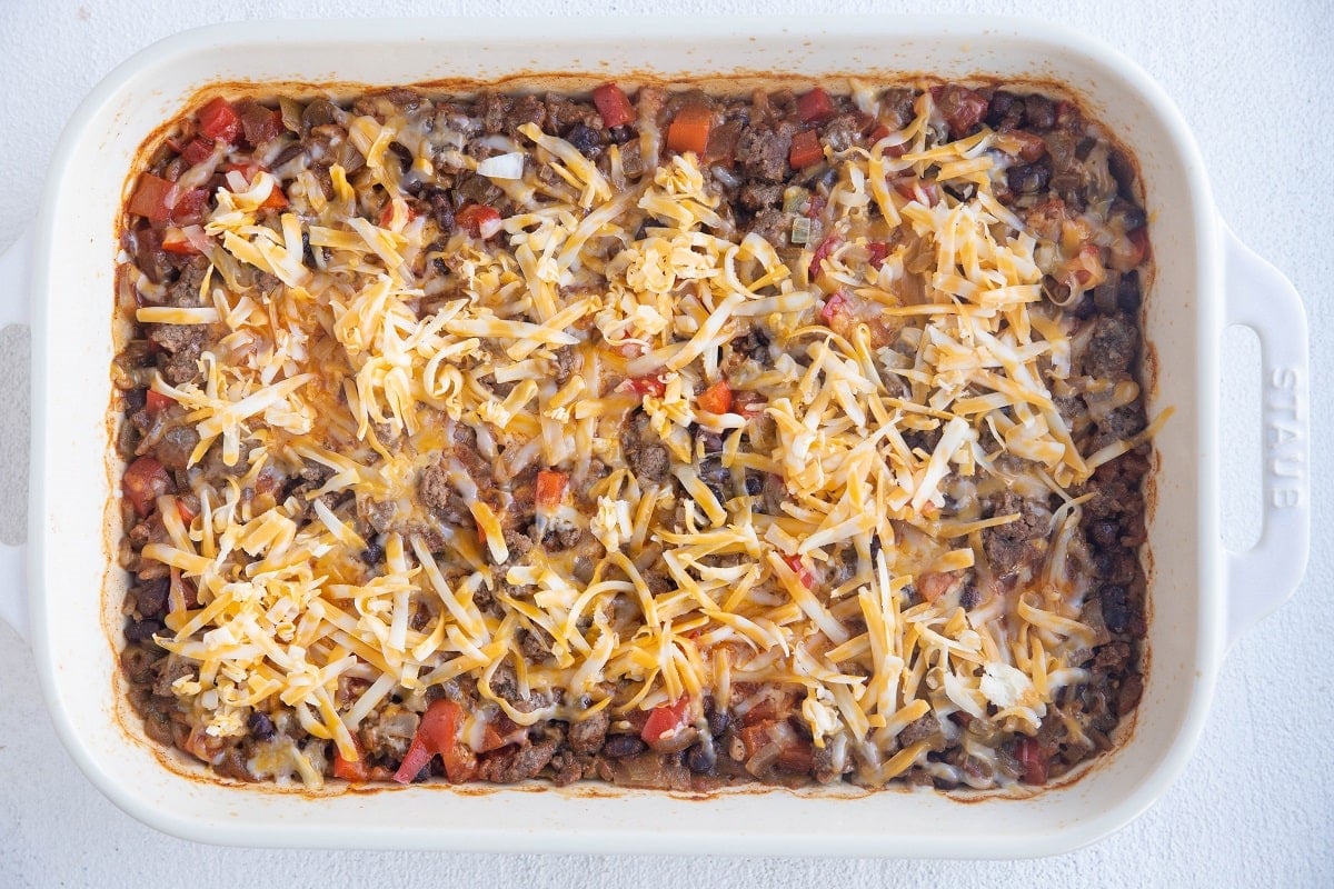 Partially baked casserole with cheese on top.
