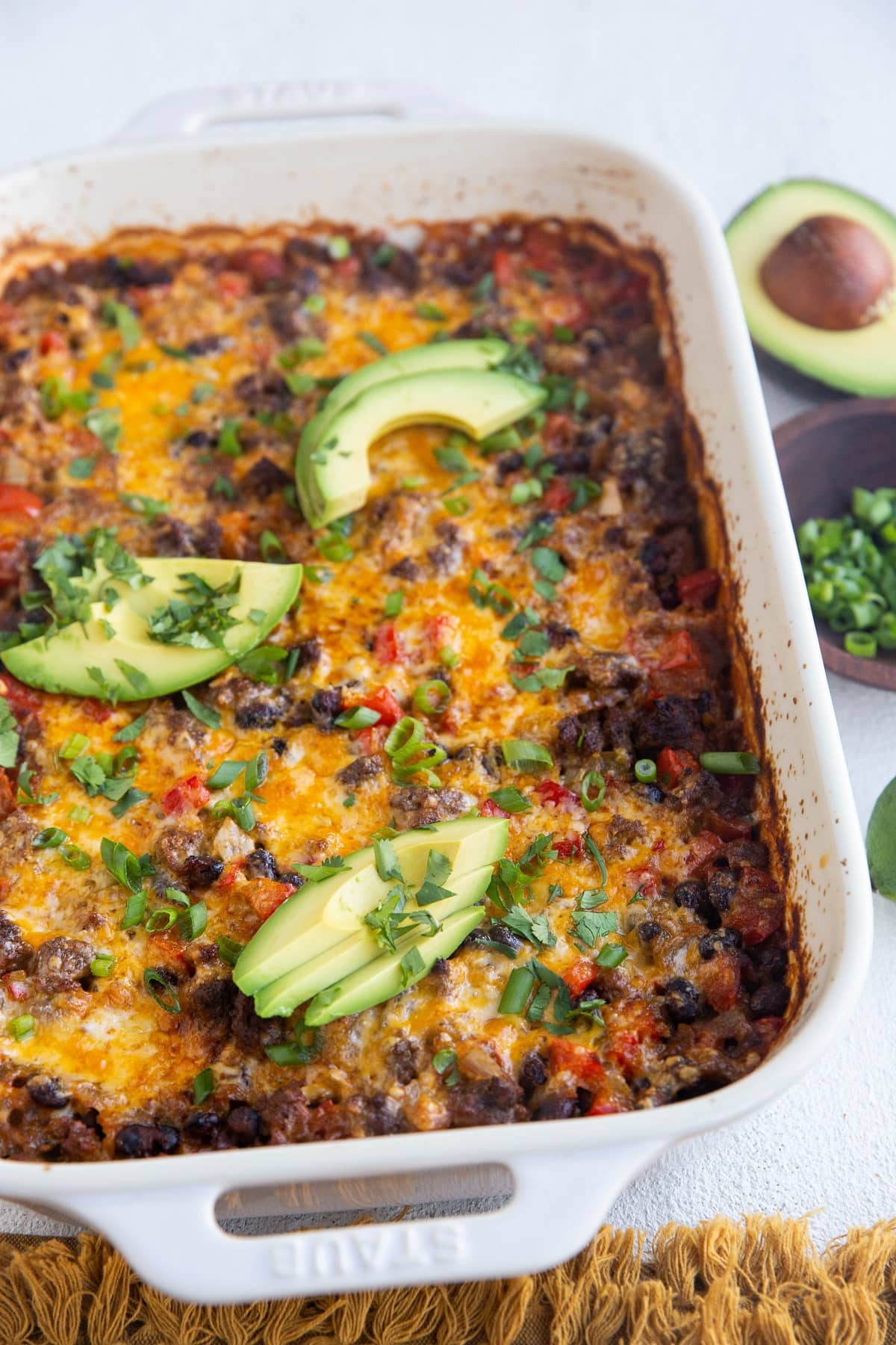 Casserole dish with taco casserole inside and a golden napkin.