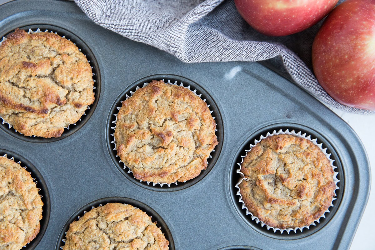Apple cinnamon muffins in a muffin tray fresh out of the oven.