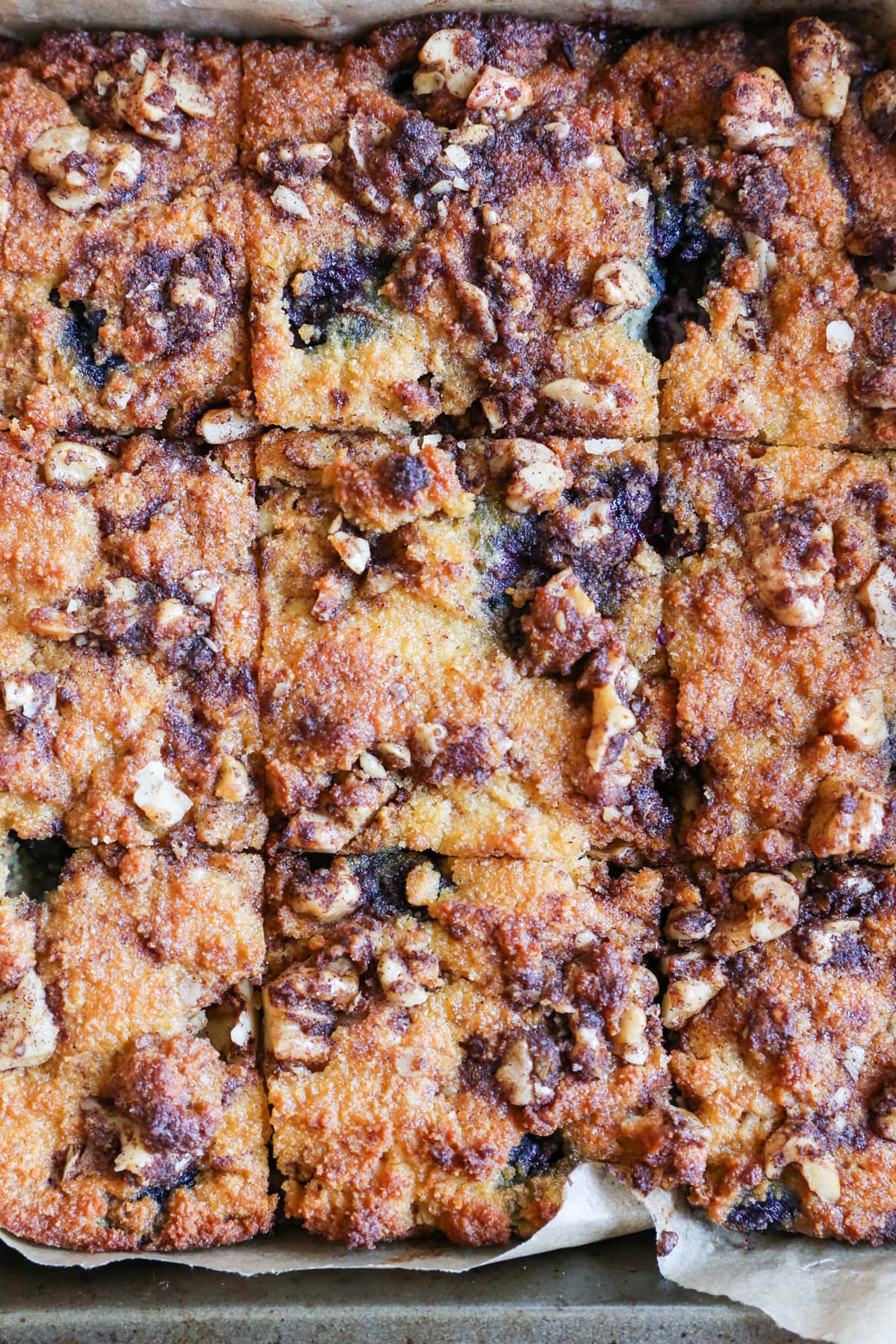 Baking pan of healthy blueberry coffee cake cut into slices, ready to serve.