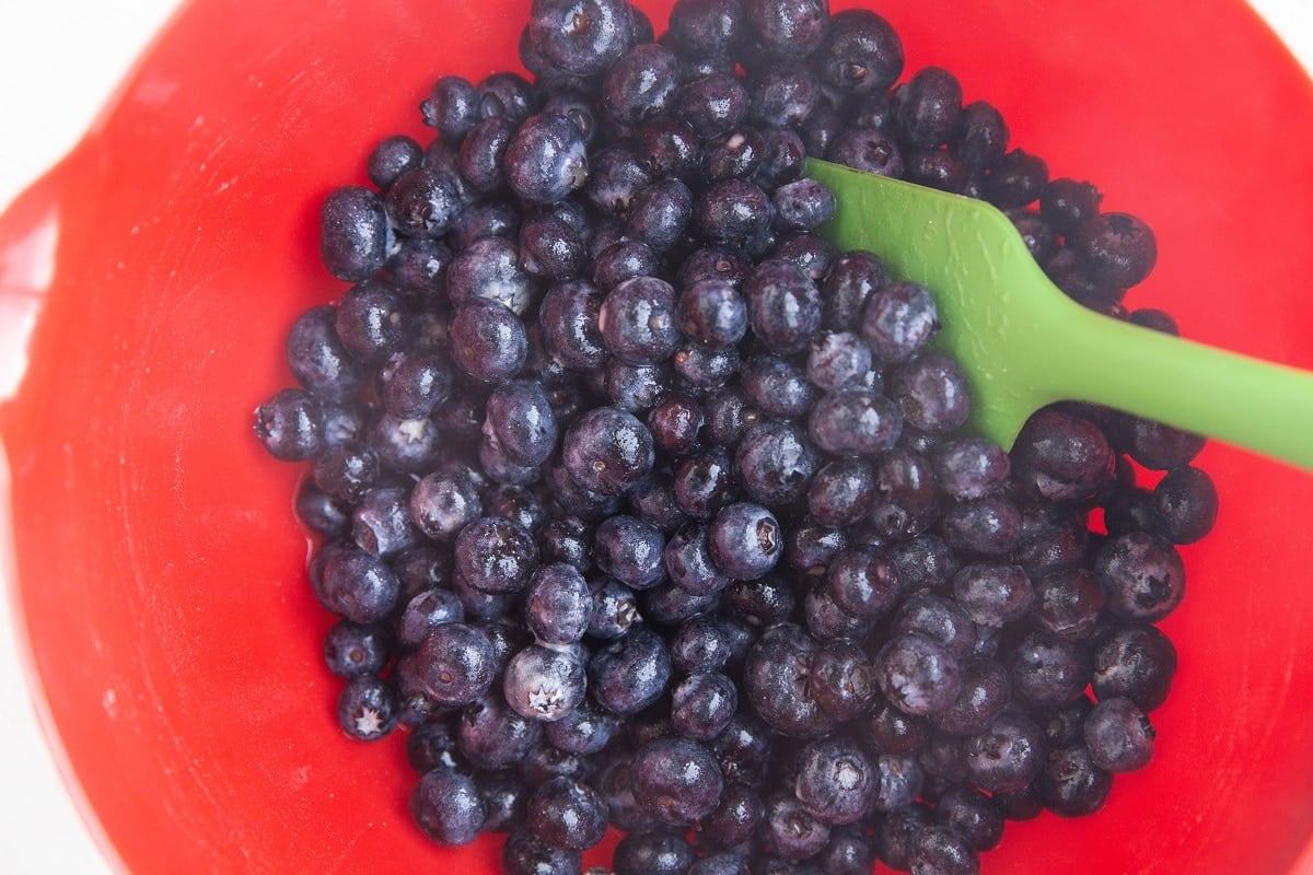 Blueberries stirred up with pure maple syrup and flour in a mixing bowl.