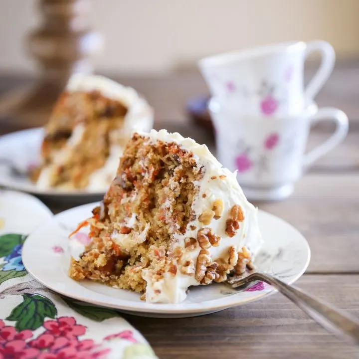 Two slices of healthy carrot cake made with almond flour on plates with cups of tea.