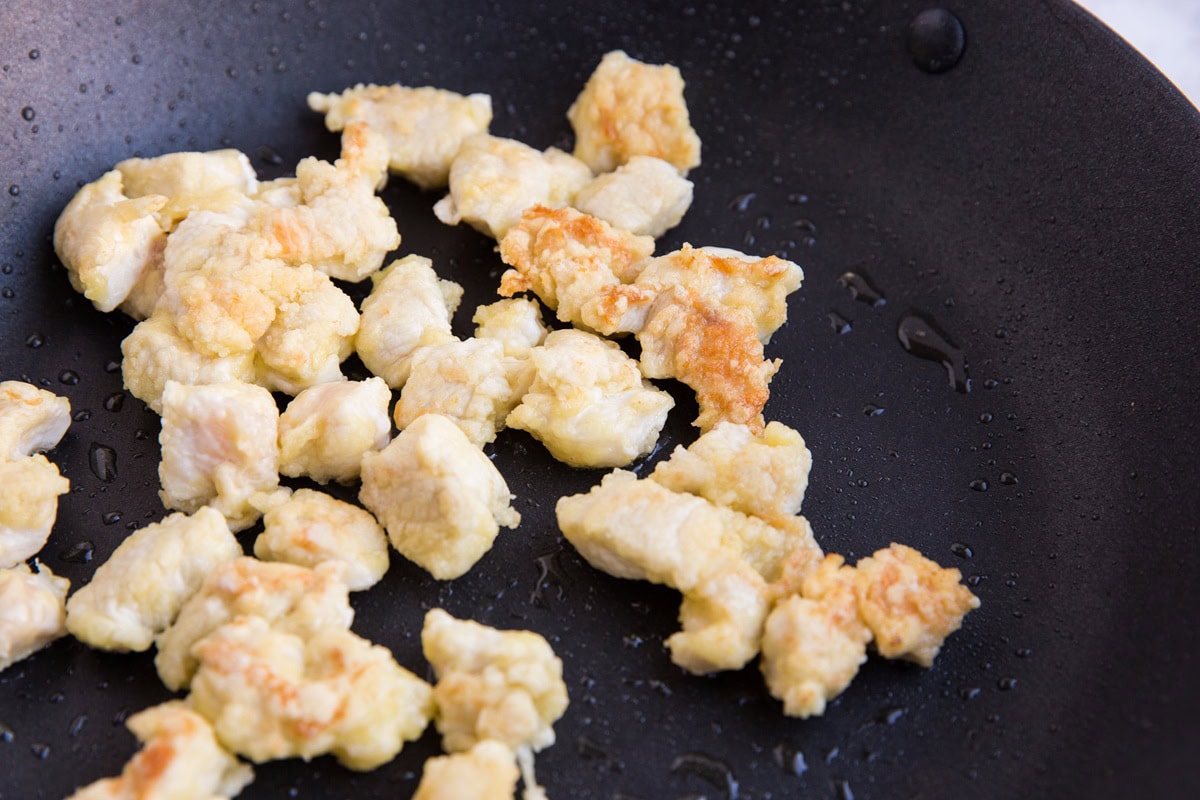 pan-fried chicken for general chicken. breaded chicken browning in a frying pan.