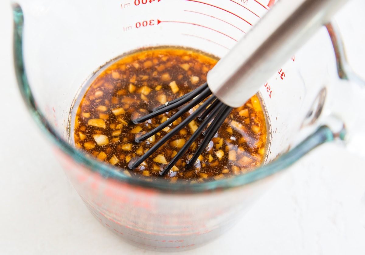 Sauce for paleo general chicken in a measuring cup with a whisk inside.