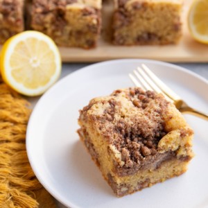 Slice of lemon coffee cake on a plate with slices of coffee cake in the background.