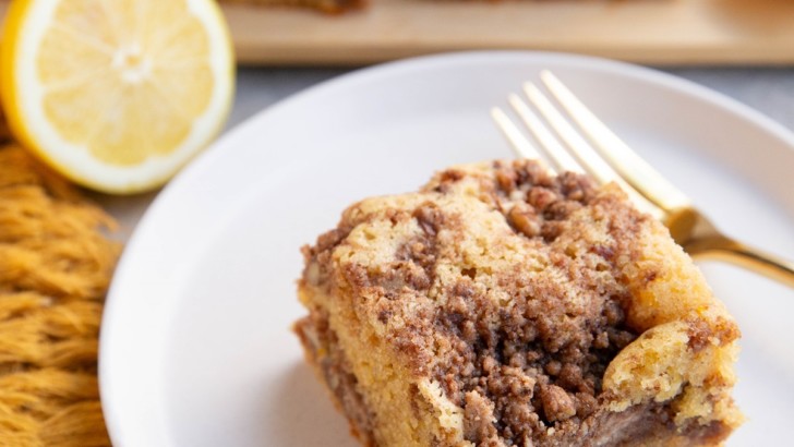 Slice of lemon coffee cake on a plate with slices of coffee cake in the background.