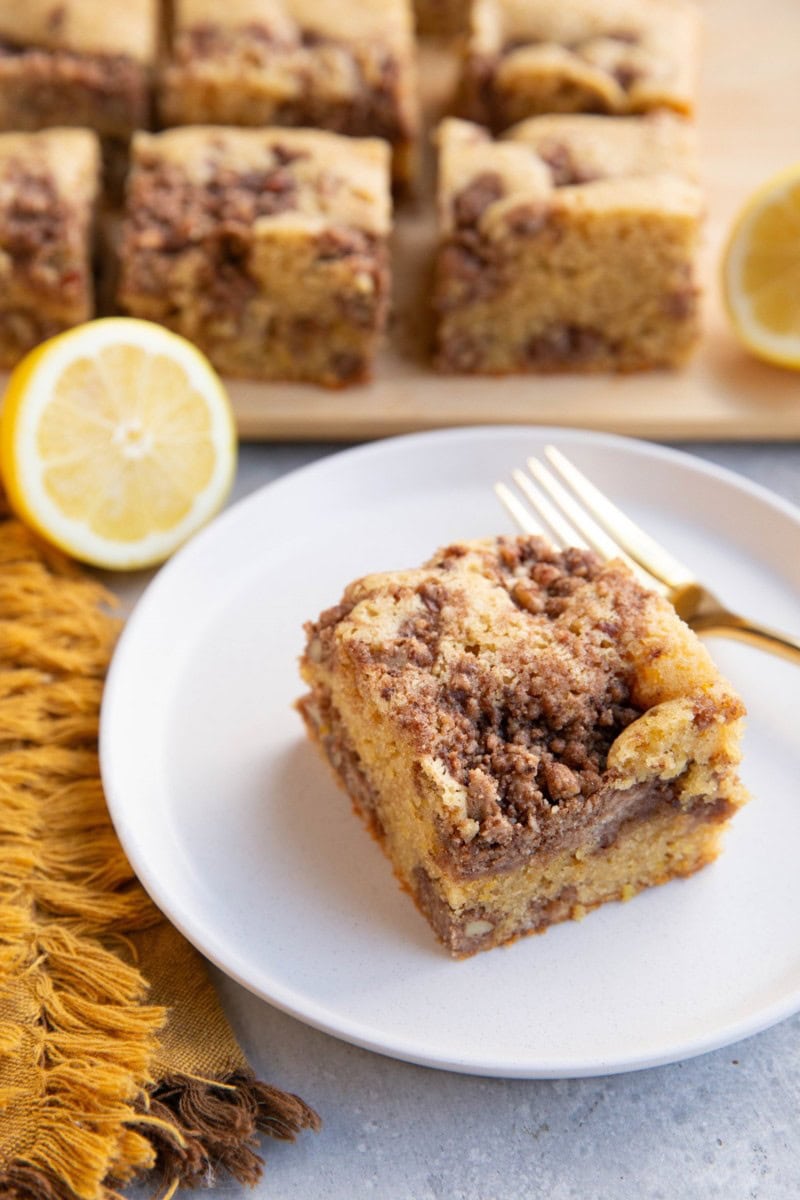 Slice of lemon coffee cake on a plate with slices of coffee cake in the background.